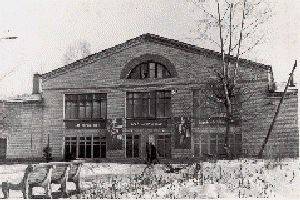 Районный дом культуры (РДК). Здание построено в 1966 году, начало работать с 1 января 1967 года. На фасаде — плакат.
